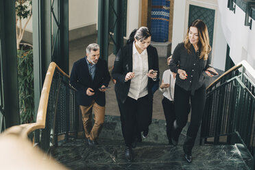 Geschäftsleute in voller Länge, die auf einer Treppe im Büro gehen - MASF08357