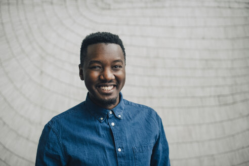 Portrait of smiling businessman against gray wall - MASF08384