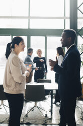 Businessman sharing ideas with female coworker in meeting at office - MASF08414