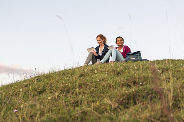 Niedriger Blickwinkel von Mutter und Tochter auf einem Hügel im Park sitzend gegen den Himmel - MASF08423