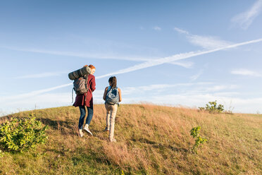 Niedriger Blickwinkel von Mutter und Tochter, die sich im Park bergauf bewegen, vor blauem Himmel - MASF08435