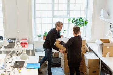 Hoher Blickwinkel von Geschäftskollegen, die Kartons am Fenster in einem kreativen Büro stapeln - MASF08484