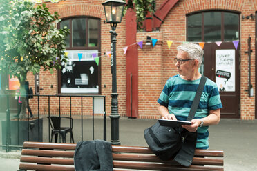 Älterer Mann benutzt ein digitales Tablet, während er an einem Gebäude in der Stadt steht - MASF08535
