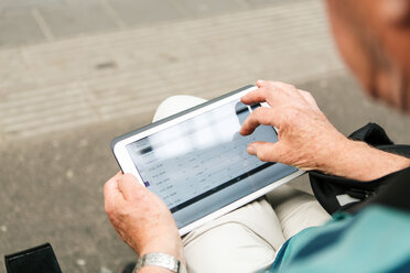 Hoher Blickwinkel eines älteren Mannes, der ein digitales Tablet benutzt, während er in der Stadt sitzt - MASF08537