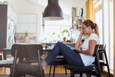 Side view of woman watching digital tablet while sitting on chair at home - MASF08548