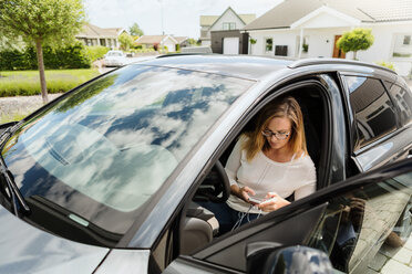 High angle view of woman using mobile phone while sitting in car on sunny day - MASF08558