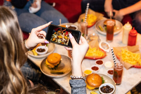 Abgeschnittenes Bild von Teenager-Mädchen fotografiert Essen und Getränke auf dem Tisch im Restaurant serviert - MASF08563