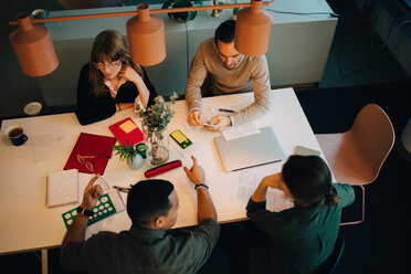 High angle view of multi-ethnic business team discussing while sitting at desk in creative office - MASF08591