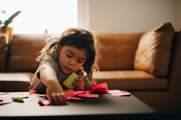 Boy playing with adhesive notes on coffee table at office lobby - MASF08604