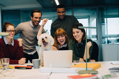 Excited business team with dog at desk in creative office stock photo