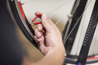 Nahaufnahme einer Person bei der Verwendung eines Speichenschlüssels an einem Fahrradrad - CUF40134