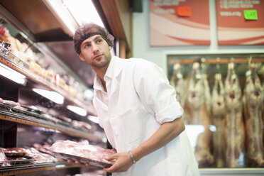 Butcher holding packet of meat in butcher's shop - CUF40160