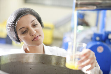 Frau hält Becher mit Olivenöl in einer Olivenverarbeitungsanlage - CUF40165