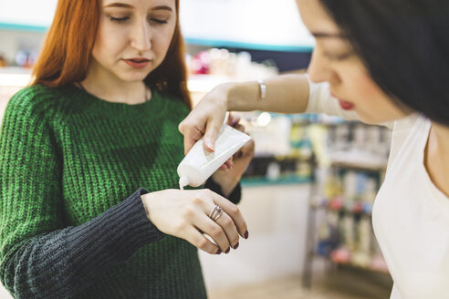 Zwei Frauen in einem Kosmetikgeschäft probieren Handcreme - WPEF00660