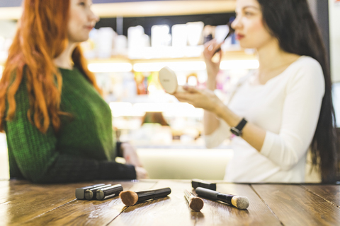 Zwei Frauen in einem Kosmetikgeschäft probieren Make-up aus, lizenzfreies Stockfoto