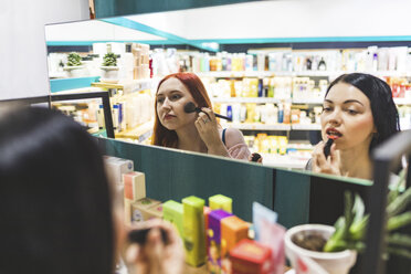 Zwei Frauen in einem Kosmetikgeschäft probieren Make-up aus - WPEF00673