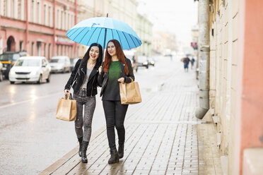 Zwei glückliche Frauen beim Einkaufen in der Stadt an einem regnerischen Tag - WPEF00674