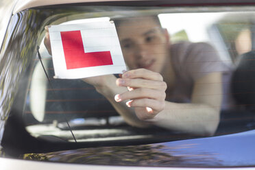 Learner driver placing letter L on rear window of car - ZEF15779