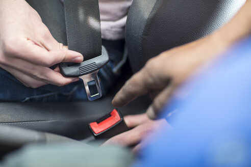 Male hands in car fastening safety belt - ZEF15780