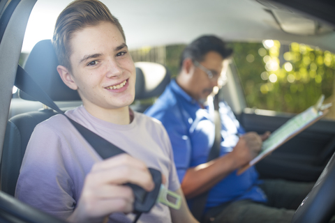 Portrait of smiling learner driver with instructor in car stock photo