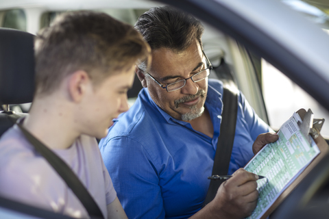 Learner driver with instructor in car looking at test script stock photo