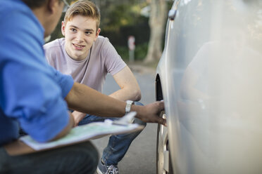 Fahrschüler mit Fahrlehrer bei der Reifenkontrolle an einem Auto - ZEF15802