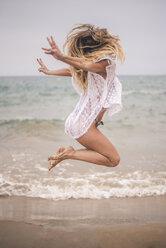 Glückliche junge Frau springt am Strand - ACPF00099