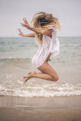 Happy young woman jumping on the beach - ACPF00099