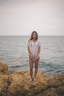 Porträt einer jungen Frau, die auf einem Felsen an der Küste steht - ACPF00109