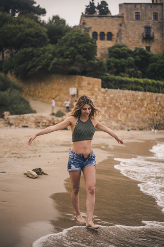 Schöne junge Frau beim Spaziergang am Strand, lizenzfreies Stockfoto