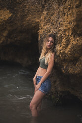 Schöne junge Frau steht an einem Felsen im Meer - ACPF00114