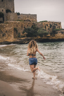 Rückansicht einer jungen Frau beim Laufen am Strand - ACPF00116