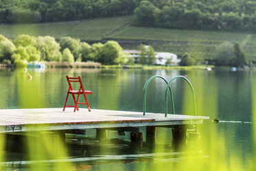 Stuhl auf einem Holzsteg in einem stillen ländlichen See - CUF40220
