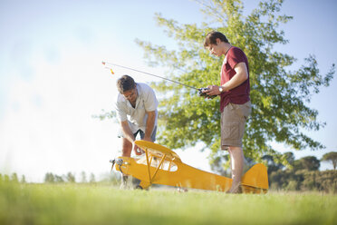 Männer spielen mit Spielzeugflugzeug im Park - CUF40306