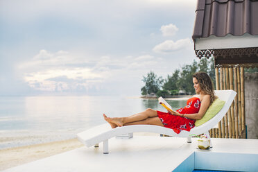 Thailand, Koh Phangan, Frau liest Buch am Strand - MOMF00470