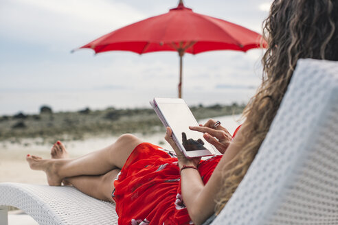 Thailand, Frau benutzt digitales Tablet am Strand - MOMF00473