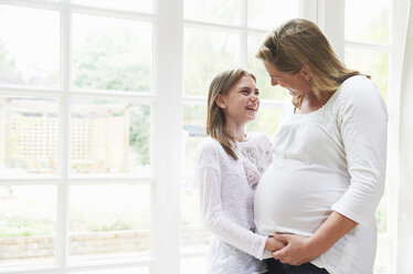 Pregnant mother with teenage daughter by window - CUF40358