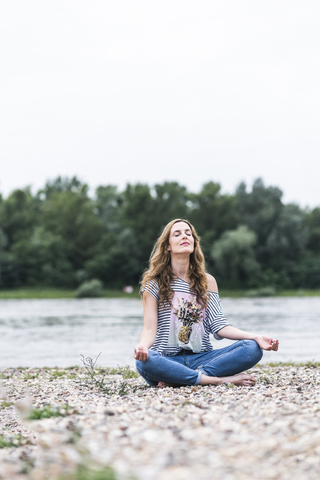 Woman practicing yoga at the riverside stock photo