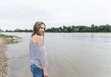 Smiling woman standing at the riverside - UUF14447