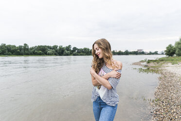 Smiling woman standing at the riverside - UUF14449