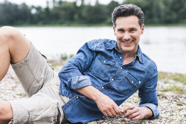 Portrait of smiling man relaxing at the riverside - UUF14457