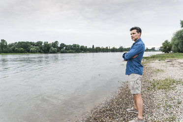 Man standing at the riverside looking out - UUF14461