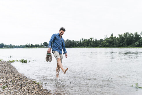 Smiling man splashing water in a river - UUF14463