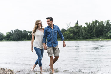 Smiling couple wading in river - UUF14465