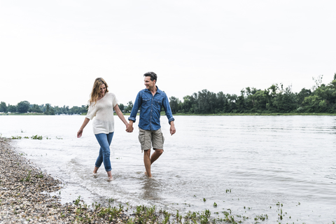 Glückliches Paar watet im Fluss, lizenzfreies Stockfoto