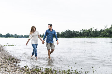 Happy couple wading in river - UUF14485