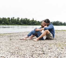 Verliebtes Paar am Flussufer sitzend - UUF14486