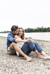 Affectionate couple sitting at the riverside - UUF14487