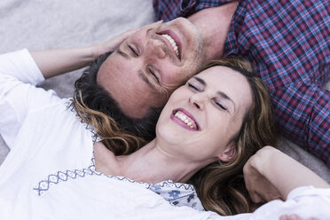 Glückliches, zärtliches Paar auf einer Decke liegend - UUF14529