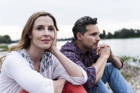 Ehepaar sitzt am Flussufer und denkt nach, lizenzfreies Stockfoto